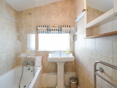 A bathroom with a bathtub sink towel and a window at 3 Argyle House Lyme Regis