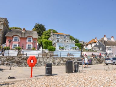 Houses with thatched and tiled roofs near a pebble beach with people sitting on benches and walking at 3 Argyle House in Lyme Regis