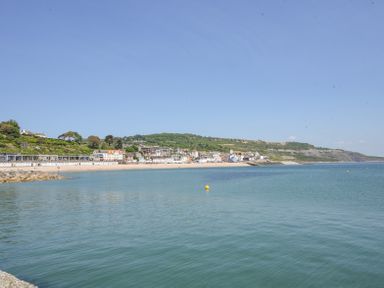 A coastal town with houses by the beach and calm sea under a clear sky at 3 Argyle House in Lyme Regis