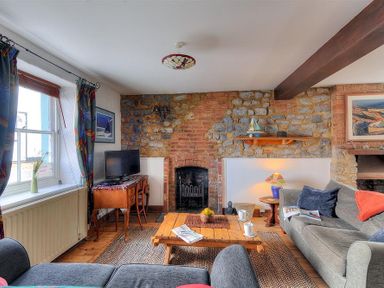 A living room with stone and brick walls a wooden coffee table and sofas at Bedrock in Lyme Regis