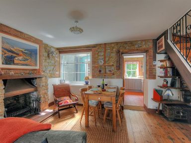 A dining area with wooden table and chairs near a fireplace and staircase at Bedrock in Lyme Regis