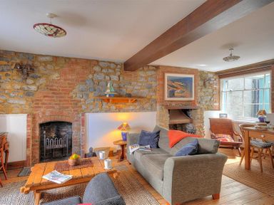 A sitting room with stone walls a wooden coffee table and sofas at Bedrock in Lyme Regis