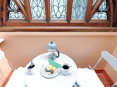 A small round table with two cups of coffee and a plate of cookies between two white chairs near a window with decorative wooden frame at Bedrock in Lyme Regis