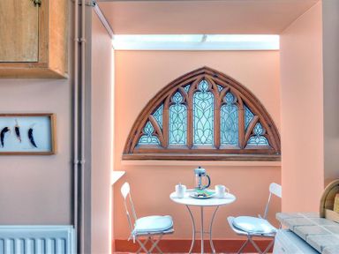 A small dining area with two chairs a round table and a stained glass window at Bedrock in Lyme Regis