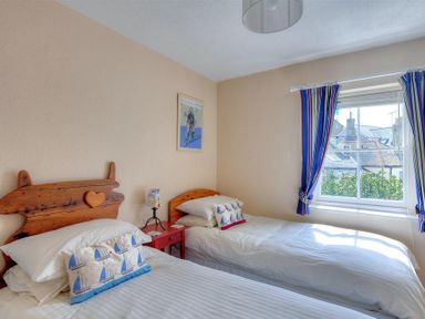 A bedroom with two single beds a red bedside table and a window with striped curtains at Bedrock in Lyme Regis