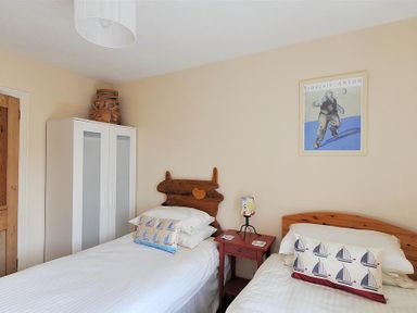 A bedroom with two single beds a red nightstand and a white wardrobe at Bedrock in Lyme Regis