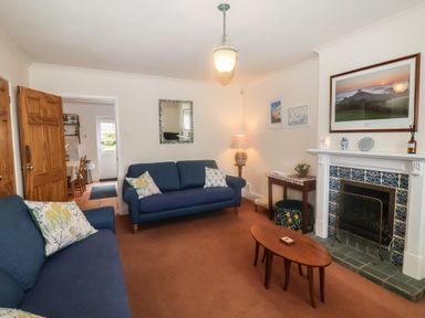A living room with blue sofas a wooden coffee table and a fireplace at 2 Kersbrook Gardens Lyme Regis
