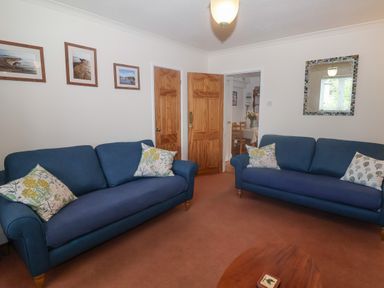 A living room with two blue sofas and wooden doors at 2 Kersbrook Gardens in Lyme Regis