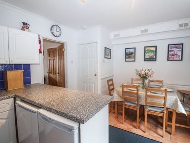 A kitchen countertop with a bread box and a dining table set with chairs and plates at 2 Kersbrook Gardens in Lyme Regis