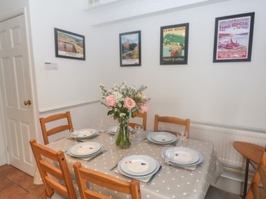 A dining room with a polka dot tablecloth on a table set for six with a vase of flowers on the table and framed pictures on the wall at 2 Kersbrook Gardens Lyme Regis