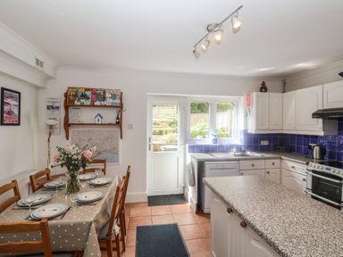 A kitchen and dining area with a table set for six and a door leading outside at 2 Kersbrook Gardens in Lyme Regis