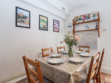 A dining room with a table set for six with plates and glasses and a vase of flowers on the table at 2 Kersbrook Gardens in Lyme Regis