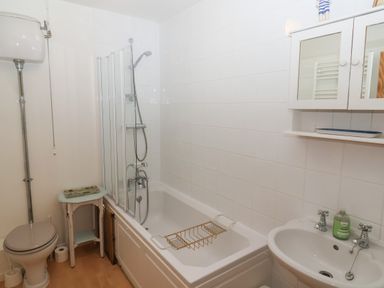 A bathroom with a bathtub shower toilet sink and a small table at 2 Kersbrook Gardens Lyme Regis