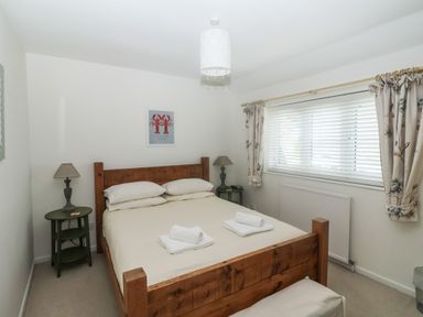 A bedroom with a wooden double bed two side tables with lamps a window with floral curtains and blinds at 2 Kersbrook Gardens Lyme Regis