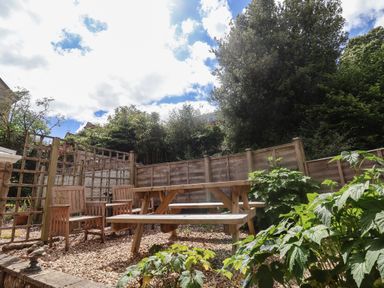 A garden area with wooden picnic table and chairs surrounded by wooden fencing and plants at 2 Kersbrook Gardens in Lyme Regis