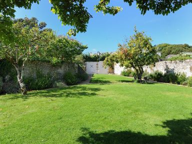 A garden with grass trees and stone walls at The Lower Deck in Lyme Regis