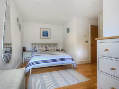 A bedroom with a double bed bedside tables a rug and a mirror on the wall at The Lower Deck in Lyme Regis