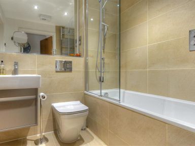 A bathroom with a toilet sink and bathtub with glass shower screen at The Lower Deck in Lyme Regis
