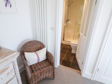 A bathroom with a shower and toilet seen from an adjacent room at Seagull in Lyme Regis
