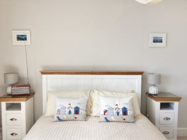 A bedroom with a bed framed by two bedside tables each with a lamp and two small framed pictures on the wall at 9 Bay View Court Lyme Regis