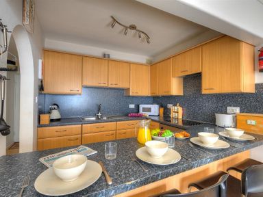 A kitchen with wooden cabinets a countertop set with bowls plates and cutlery and a pitcher of orange juice at 9 Bay View Court in Lyme Regis
