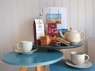 A blue two-tier table with a teapot coffee bag cups biscuits and a welcome bag at 9 Bay View Court in Lyme Regis