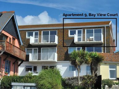 Exterior view of an apartment building with balconies and palm trees at 9 Bay View Court in Lyme Regis