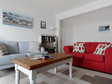 A living room with blue and red sofas a wooden coffee table and wall art at Ross House in Lyme Regis