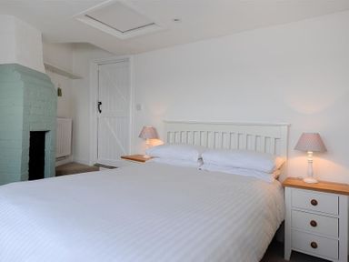 A bedroom with a white bed and bedside tables with lamps and a green fireplace at Ross House in Lyme Regis