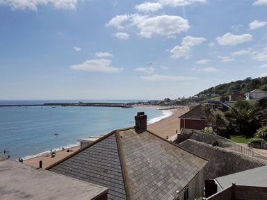 A coastal view with rooftops and a sandy beach by the sea at Ross House in Lyme Regis