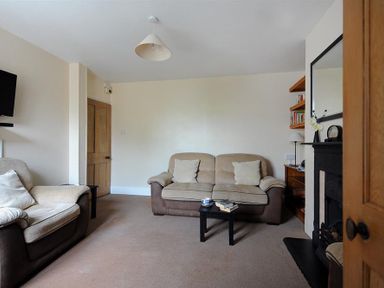 A living room with two sofas a small black table a fireplace and wooden door at 23 Lym Close Lyme Regis