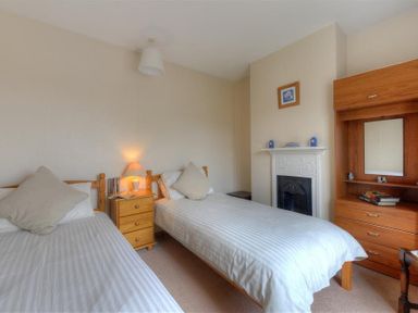 A bedroom with two single beds a wooden nightstand and a wooden dresser with a mirror at 23 Lym Close Lyme Regis