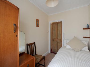 A bedroom with a wooden door bed with white striped bedding and a wooden chair and wardrobe at 23 Lym Close in Lyme Regis