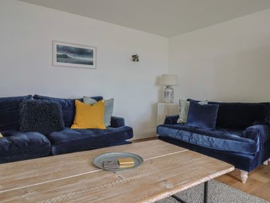 A living room with two blue sofas cushions wooden coffee table and a lamp at Ancient Lights Lyme Regis