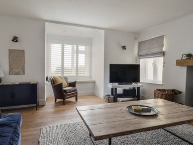 A living room with a leather chair near window a TV on stand and a wooden coffee table at Ancient Lights Lyme Regis