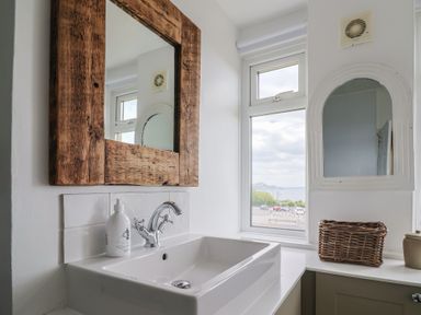A bathroom sink with a wooden framed mirror and a window showing a view outside at Ancient Lights in Lyme Regis