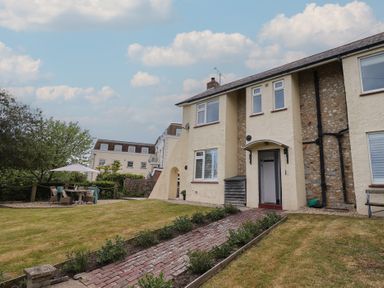 A residential building with a grass lawn a brick pathway and outdoor seating under an umbrella at Ancient Lights in Lyme Regis