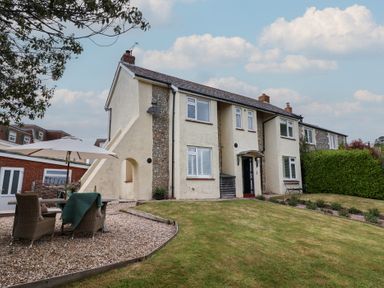 A semi detached house with a lawn and outdoor seating with an umbrella at Ancient Lights in Lyme Regis