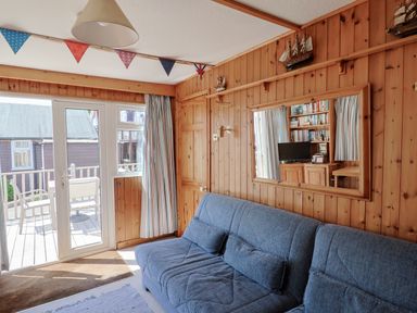 A sitting room with a grey sofa and a large mirror on wooden walls at Granny's Teeth in Lyme Regis