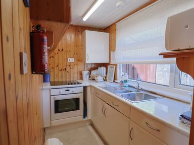 A kitchen with wooden walls a white oven a sink and a window with a blind at Granny's Teeth Lyme Regis