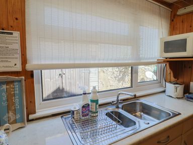 A kitchen sink area with cleaning bottles a dish rack a microwave and a toaster at Granny's Teeth in Lyme Regis