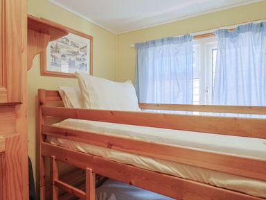 A bedroom with a wooden bunk bed and blue curtains covering a window at Granny's Teeth in Lyme Regis