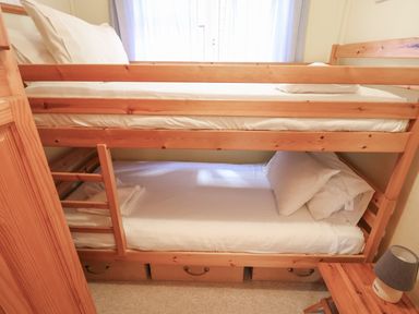 A bedroom with wooden bunk beds and a small wooden table with a lamp at Grannys Teeth Lyme Regis