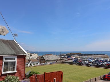 A marina with boats and parked cars near a lawn and buildings by the sea at Grannys Teeth in Lyme Regis