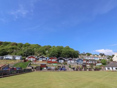 A green lawn with small houses and trees on a hillside under a blue sky at Grannys Teeth in Lyme Regis