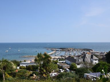 A coastal scene with a marina full of boats a beach with people houses and vegetation at Granny's Teeth in Lyme Regis
