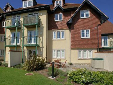 An exterior view of a residential building with balconies plants patio furniture and a storage shed at 2 Buckfields Lyme Regis
