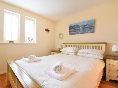 A bedroom with a wooden bed with white bedding and towels on it with two bedside tables and lamps at 2 Buckfields Lyme Regis