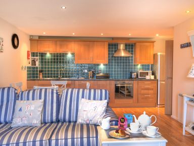 A kitchen with wooden cabinets blue tiled backsplash and a striped sofa with cushions at 2 Buckfields Lyme Regis
