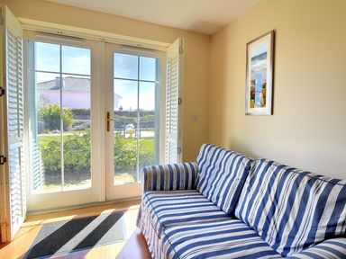 A room with a blue and white striped sofa near glass double doors with shutters at 2 Buckfields in Lyme Regis